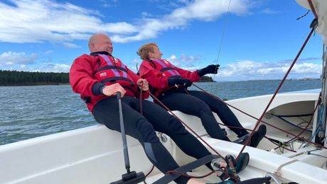 Two sailors hiking out in a dinghy on Findhorn Bay on a bright day