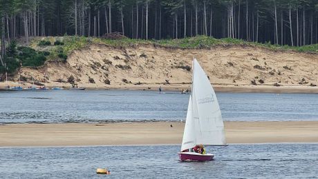 A dinghy sailing past the dunes at Culbin Sands
