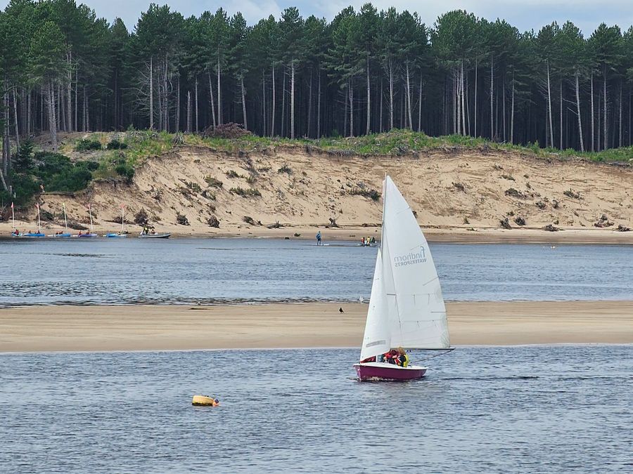 A dinghy sailing past the dunes at Culbin Sands